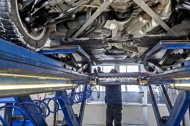 Ein Auto wird während der Hauptuntersuchung von einem Prüfer auf einer Hebebühne überprüft